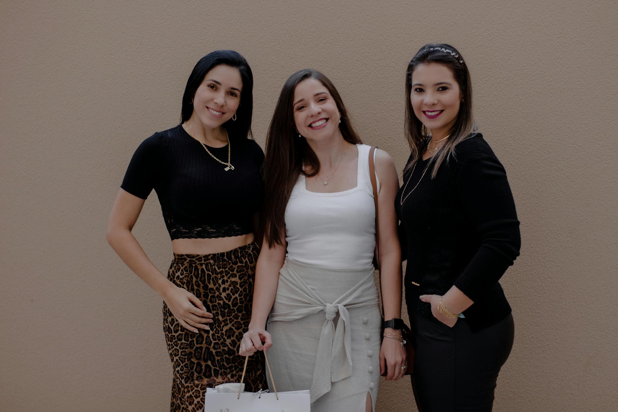 Three fashionable women posing together with shopping bags, exuding confidence and style.
